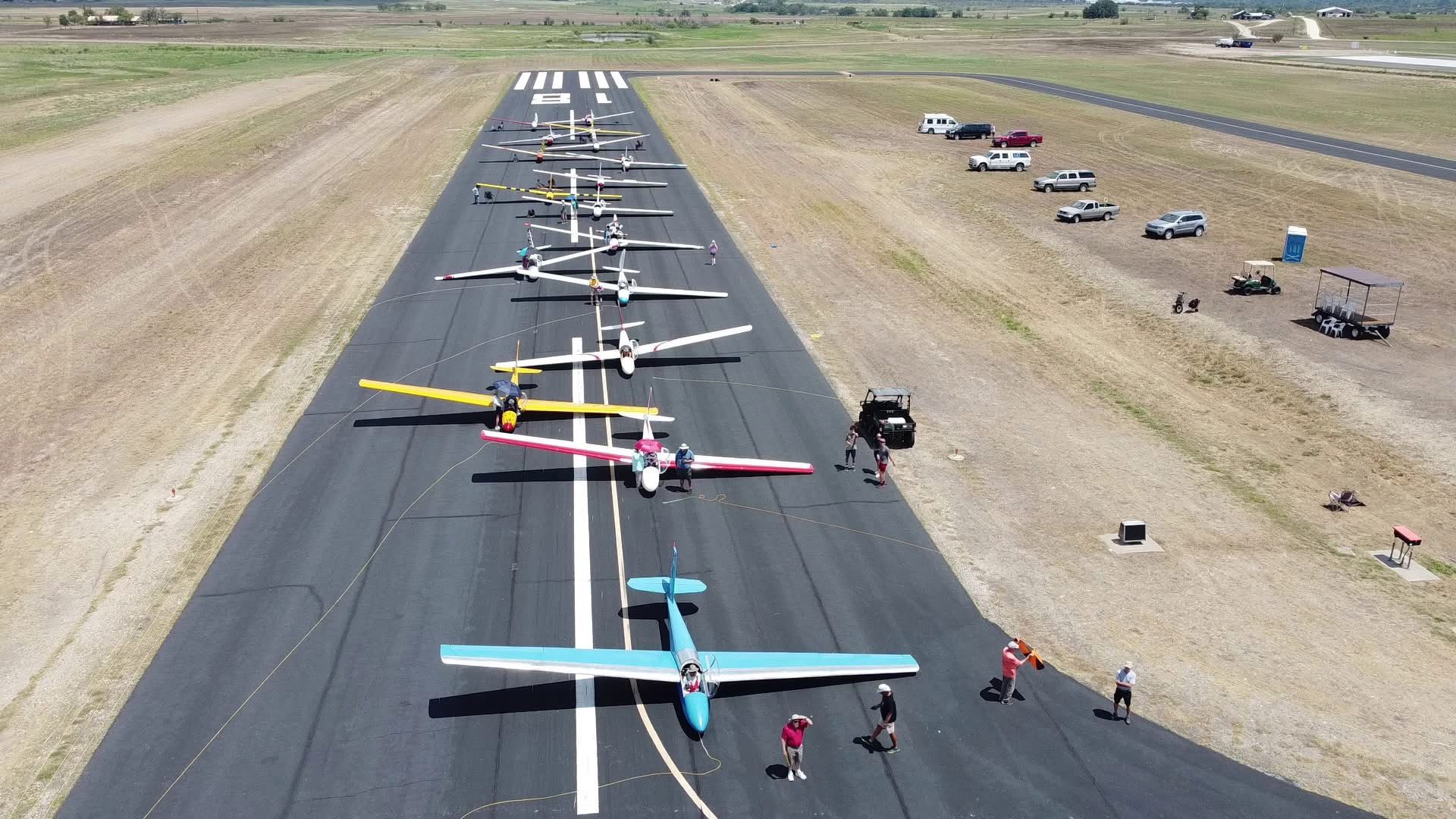 A lineup of colorful gliders staged nose-to-tail on Runway 18.